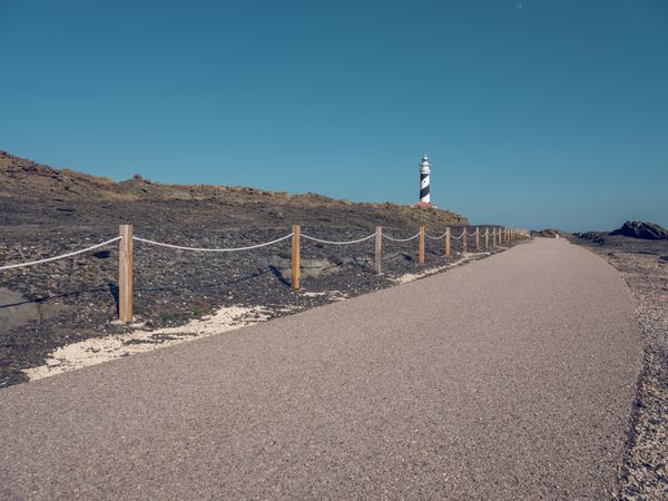 Lighthouse on top of hill and asphalt road