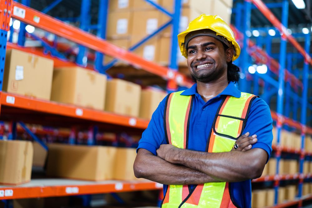 Happy employee at the factory standing with arms crossed