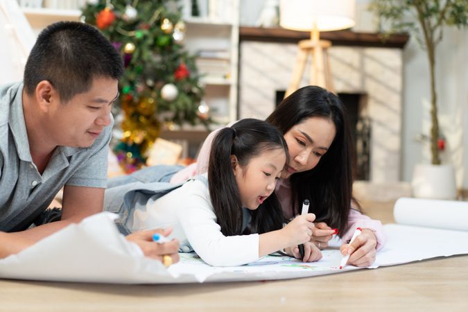Happy Asian family drawing on paper together in the living room