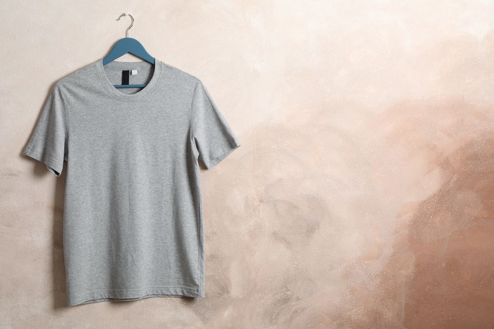 Hanger with blank gray t-shirt on brown background, space for text