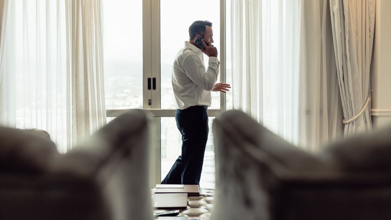Businessman talking over phone in hotel room