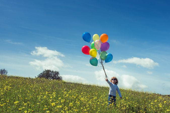 Boy with balloons in green field
