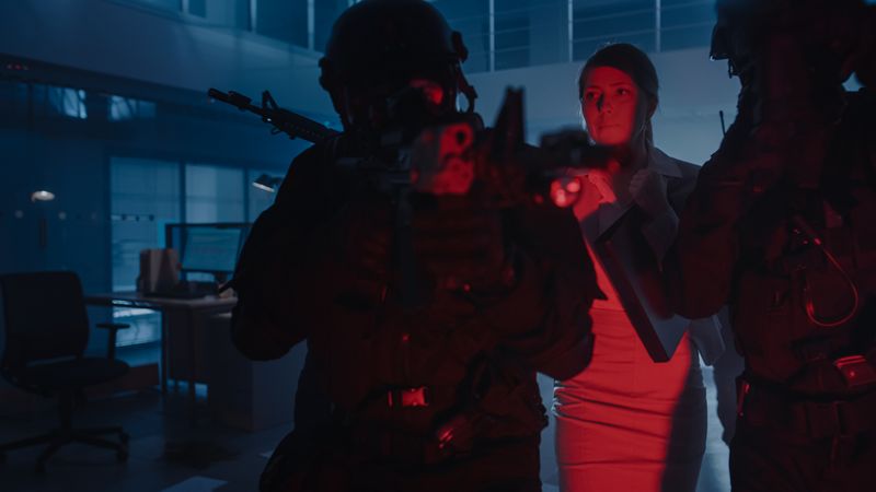 Masked Squad of Armed SWAT Police Officers Rescue a Female Hostage in a Dark Seized Office Building with Desks and Computers.