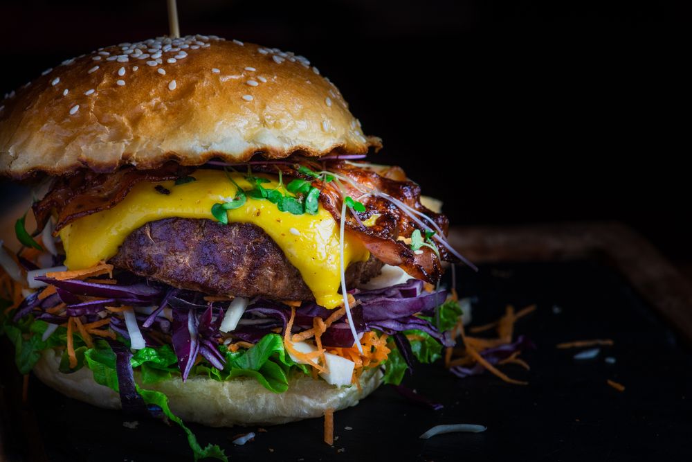 Close up of bacon burger with melted cheese and vegetables