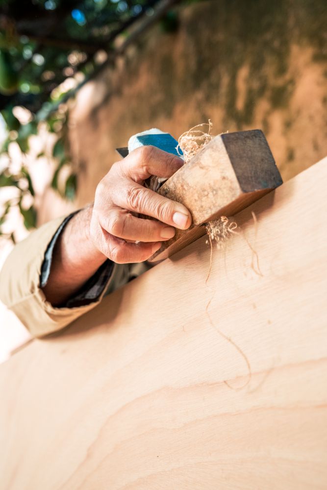 Anonymous mature man shaping wood with plane tool