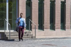 Businessman leaving office while holding a shoulder bag outdoors