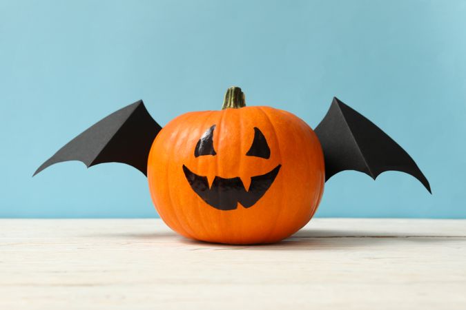 Pumpkin with smile and wings on blue background