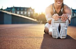 Fit woman leaning forward touching her toes warming up before workout
