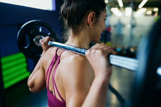 Shot of athletic woman’s back with barbell