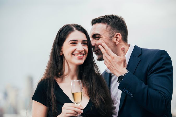Businessman whispering to businesswoman with champagne