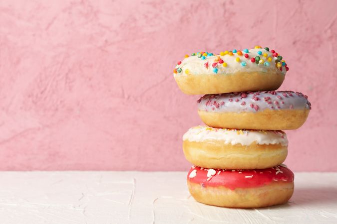 Tasty donuts on table against pink background