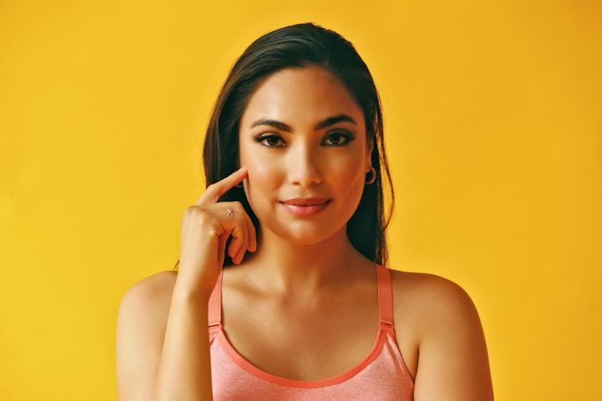 Headshot of serious Hispanic woman looking at camera in yellow room