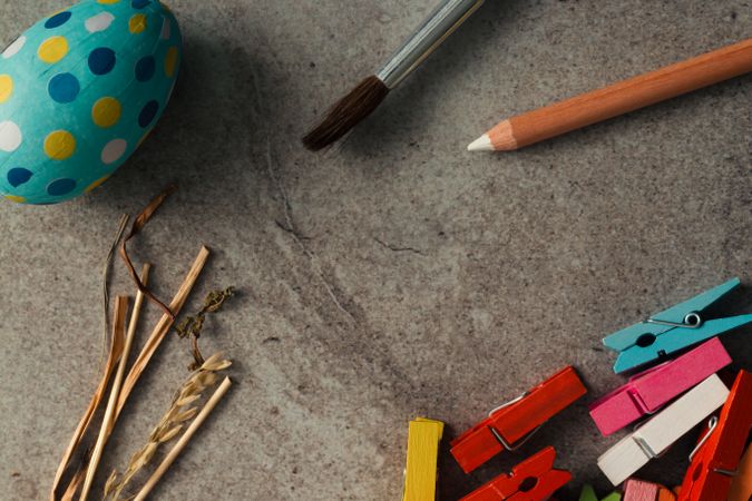 Easter egg with dots and coloring tools on stone table