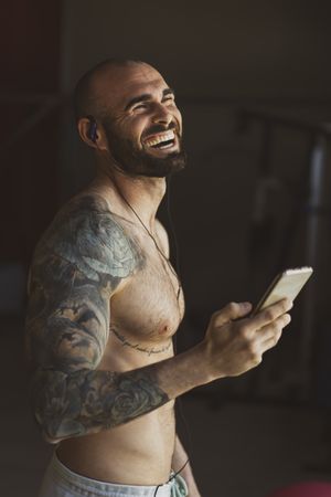 Laughing athlete with smartphone in gym