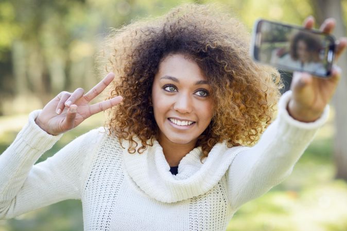 Happy Black woman taking a selfie on her phone outside