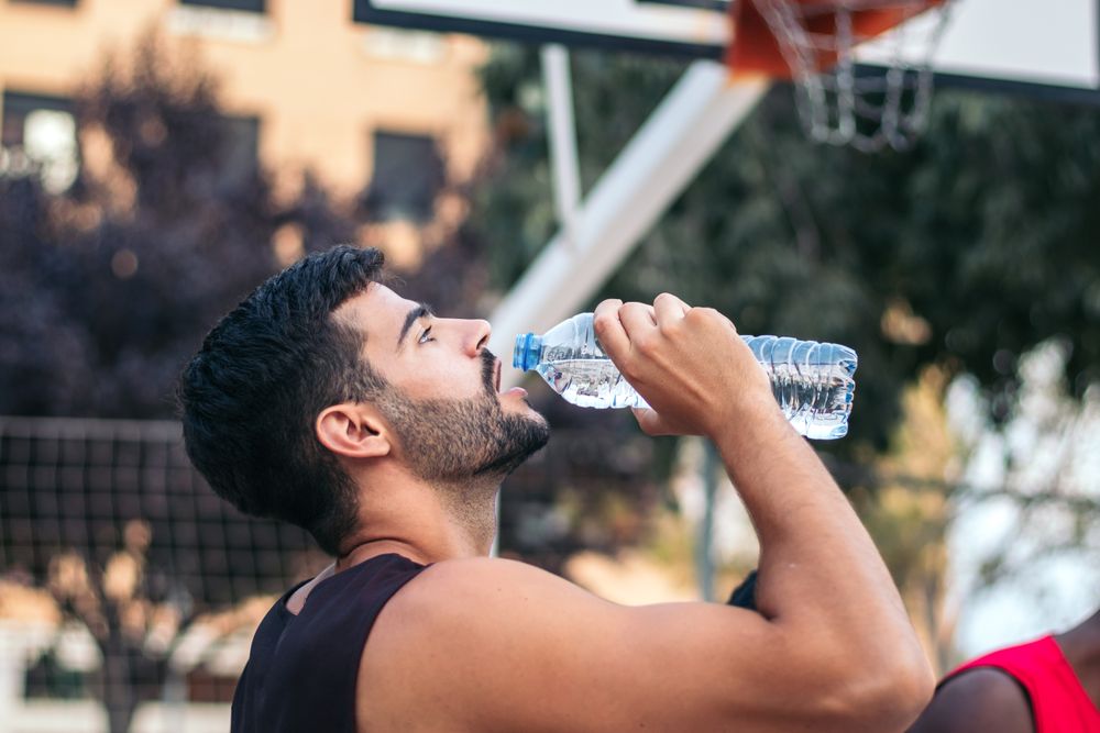 Young man drinking water after doing sports