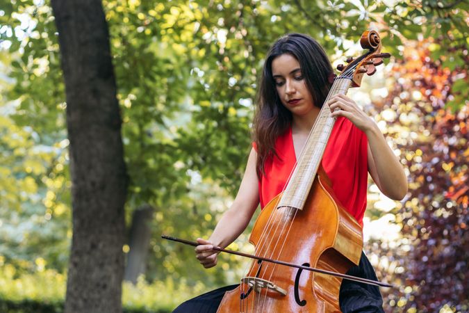 Woman playing the cello in a park.