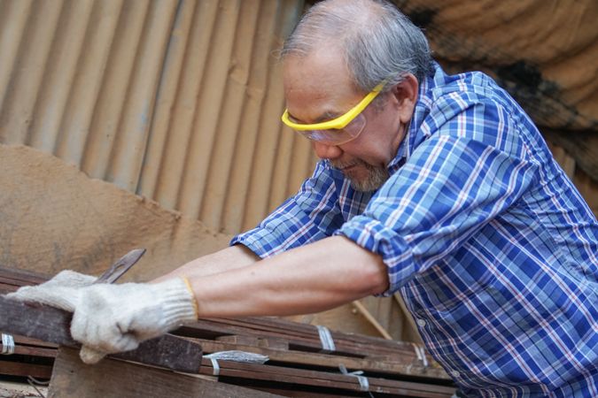 Asian carpenter in PPE working with wood in the shop