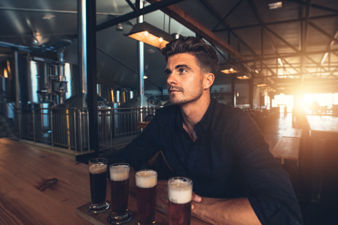Young man tasting samples of beer at brewery factory