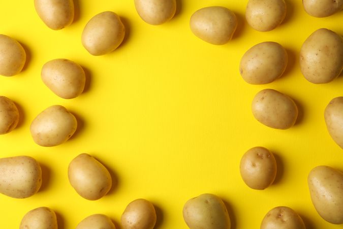 Looking down at potatoes arranged in circle, on yellow background