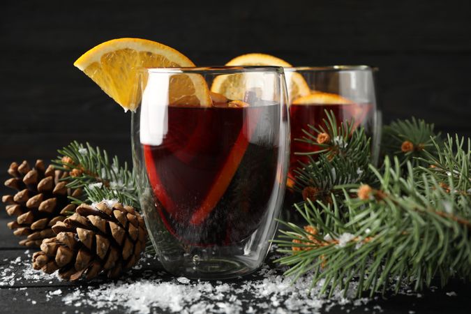 Glasses of tasty mulled with orange on decorated background, space for text