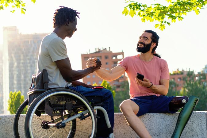 Joyful handshake between friends with disabilities outdoors