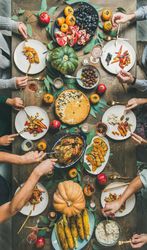 Group of people serving turkey over festive dishes, vertical composition