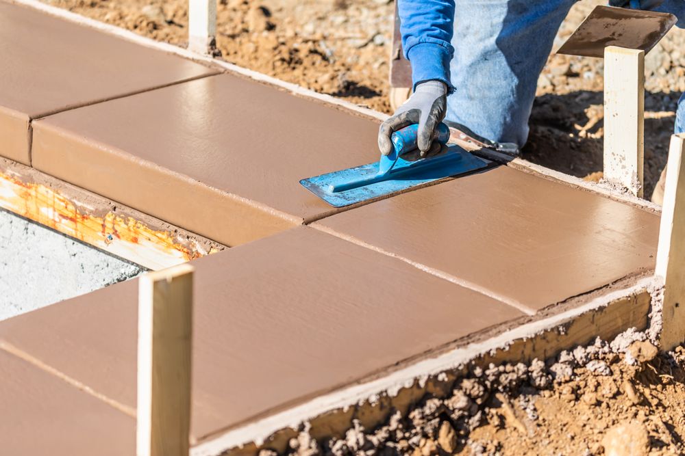 Construction Worker Using Trowel On Wet Cement Forming Coping Around New Pool