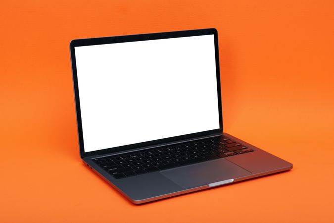 Laptop at angle with mockup screen in orange studio shoot
