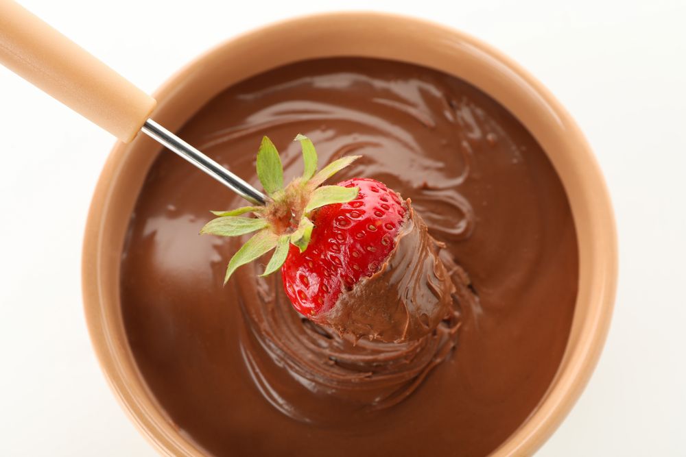Chocolate fondue. Strawberry in chocolate and bowl on plain background