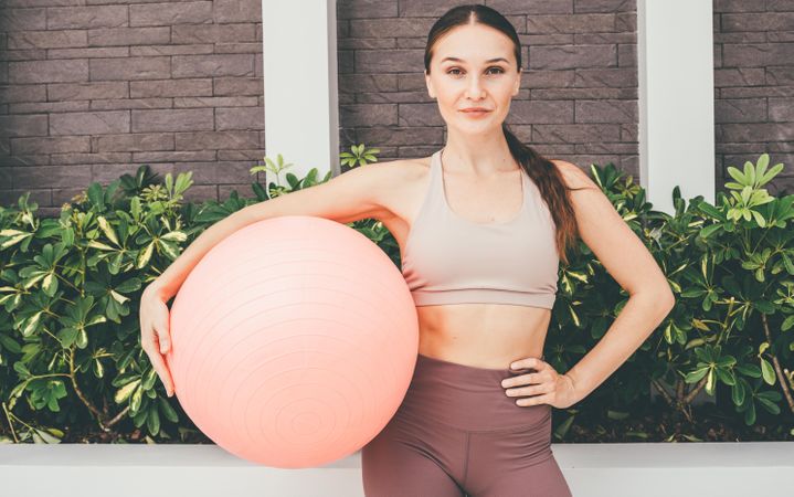 Woman standing with fitness ball on her hip