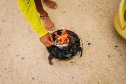 Tanned man cooking on camping stove beside parked mini van