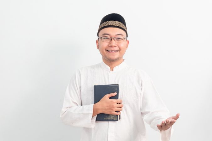 Asian Muslim man welcoming and holding quran during Ramadan
