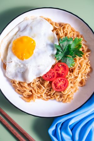 A plate of noodles with an egg and tomato on top