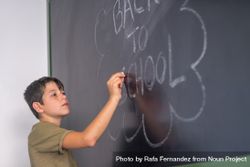 Boy writing "back to school" on chalkboard 4djKA0