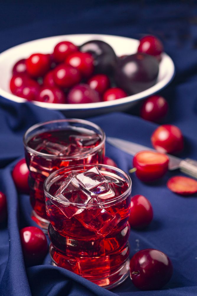 Red beverage near fresh fruits on cloth