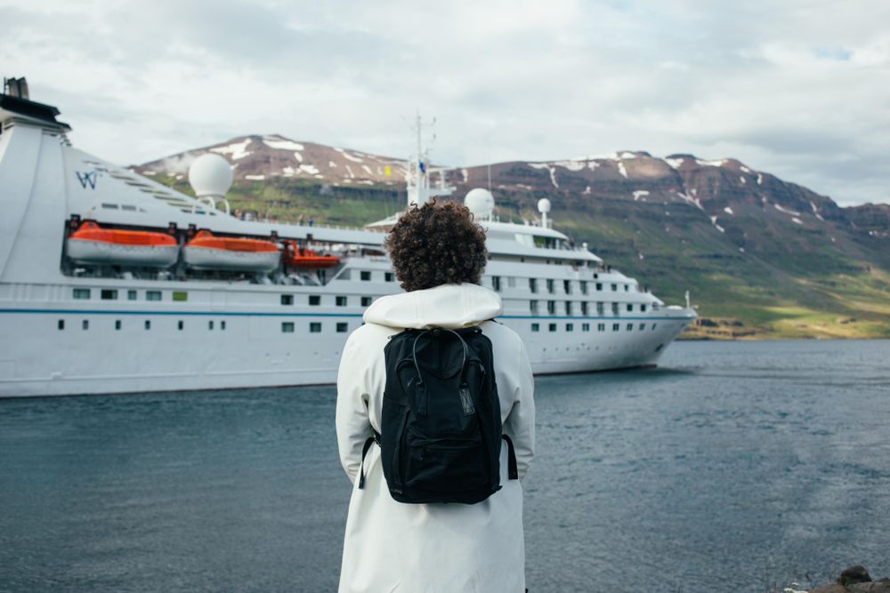 Rearview of man overlooking cruise ship in port