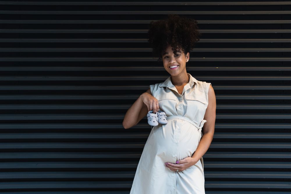 Smiling Black woman showing baby booties to camera