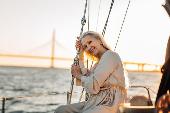 Woman relaxing on a sailboat at dusk smiling