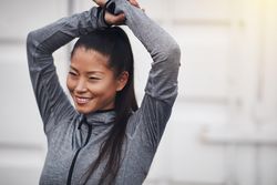 Happy woman in workout gear with arms above head
