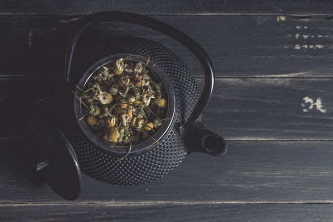 Spoonful of dried chamomile on brass teapot