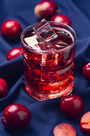Red beverage near fresh fruits on cloth