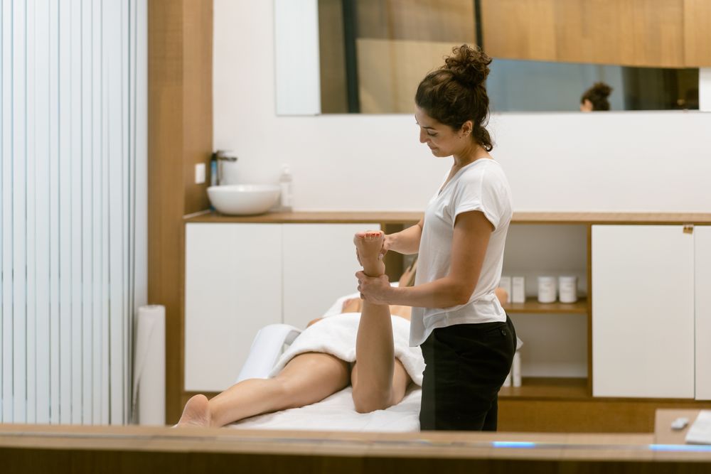 Skilled female massage therapist working on a client’s legs