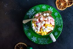 Top view of green Christmassy cup with marshmallow drink