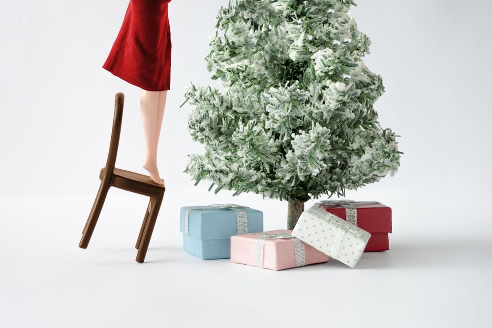 Doll standing on chair with Christmas tree with presents underneath