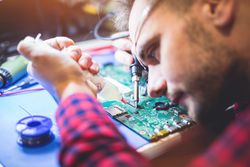 Man soldering motherboard at workplace