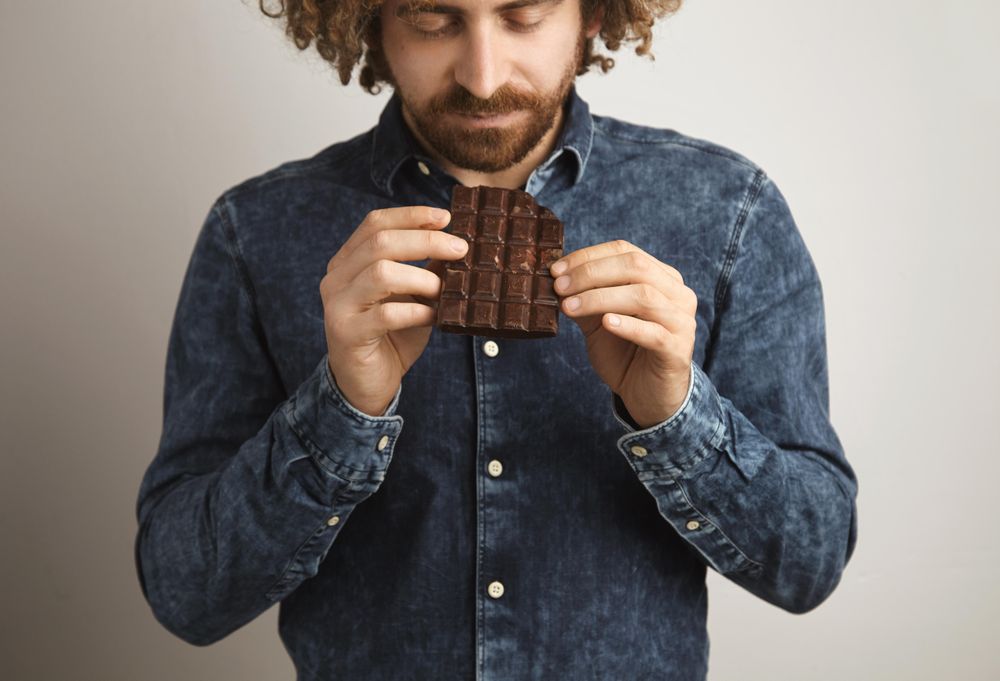 Man looking at chocolate bar he is holding