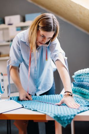 Concentrated seamstress talking on smartphone