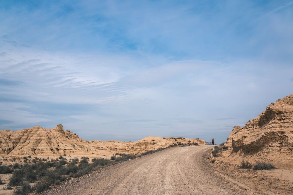 Man walking on road in desert hills