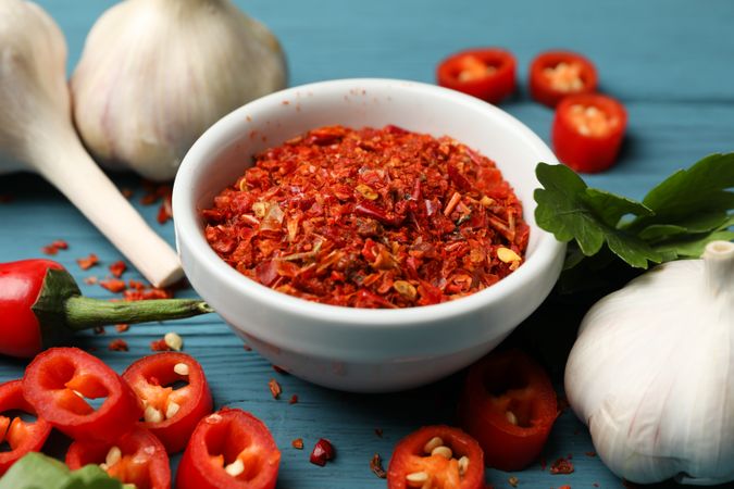 Bowl with hot powder spice, and ingredients on wooden background